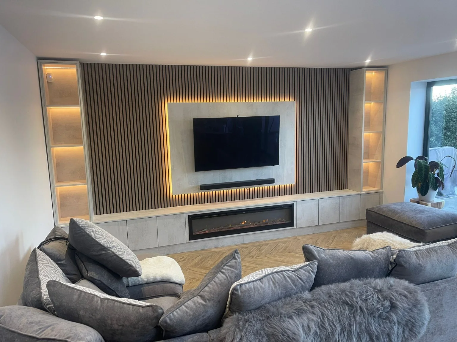 Slatted TV media wall with soundbar, illuminated shelving and electric fireplace